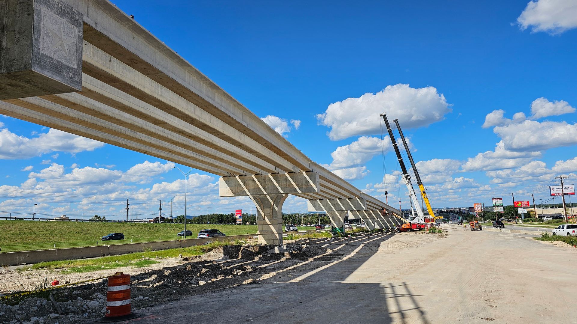 Finished elevated highway overpass built by Firmitas Construction against a blue Texas sky