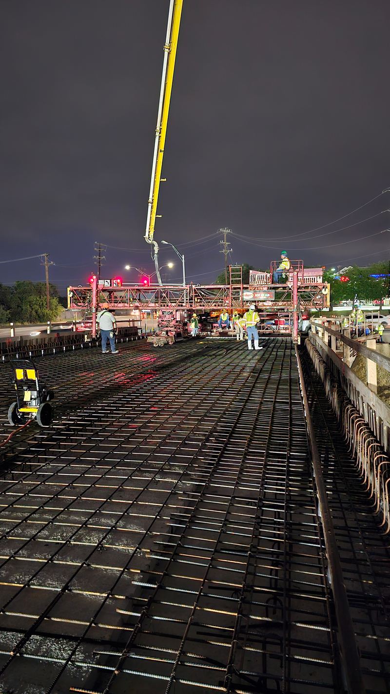 Wide view of a nighttime concrete placement with pump trucks on site